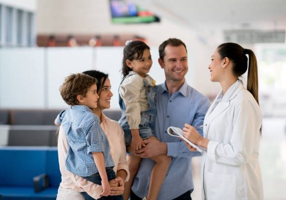 Doctor talking to a happy Latin American family at the hospital - healthcare and medicine concepts